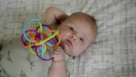 Baby-Caucasian-boy-playing-with-a-colorful-toy-on-a-white-play-mat