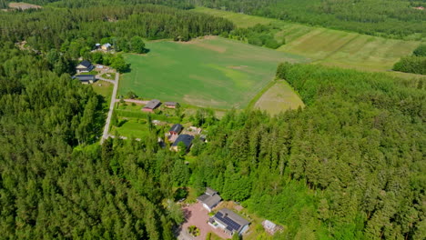 Renewable-house-in-middle-of-forest-and-fields,-summer-day---Aerial-tilt-reveal