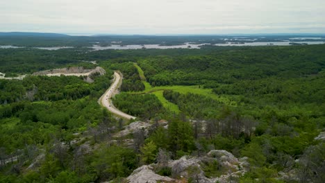 Aerial-pan-atop-mountaintop-overlooking-road-and-forest