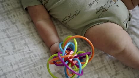 Baby-Caucasian-boy-playing-with-a-colorful-toy-on-a-white-play-mat