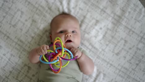 Baby-Caucasian-boy-playing-with-a-colorful-toy-on-a-white-play-mat