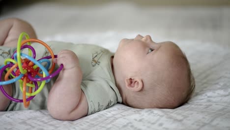 Baby-Caucasian-boy-playing-with-a-colorful-toy-on-a-white-play-mat