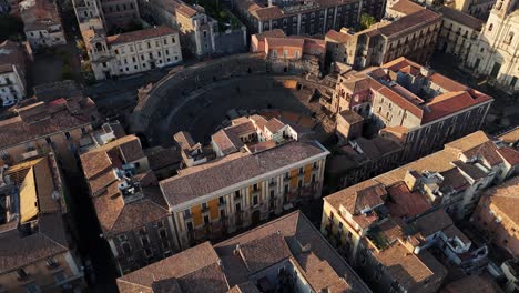 Luftaufnahme-Des-Antiken-Römischen-Amphitheaters-Und-Der-Historischen-Gebäude-In-Catania-Bei-Sonnenuntergang