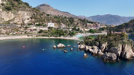 A-beautiful-coastal-town-with-blue-waters-and-rocky-formations,-aerial-view