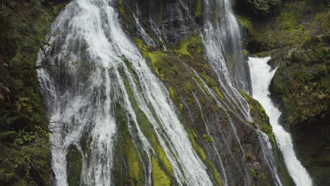 Water-from-Panther-Creek-Falls-rushing-over-moss-covered,-rocky-cliff-in-Washington-State's-Columbia-River-Gorge,-slow-rising-pedestal-shot