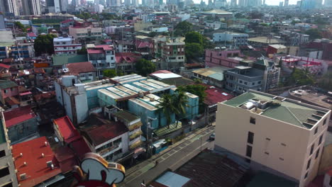 Drone-tilting-low-over-homes,-revealing-skyscrapers-of-the-Makati-city,-Philippines