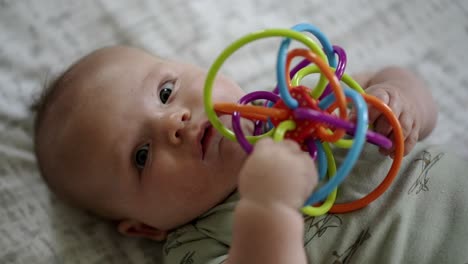 Baby-Caucasian-boy-playing-with-a-colorful-toy-on-a-white-play-mat