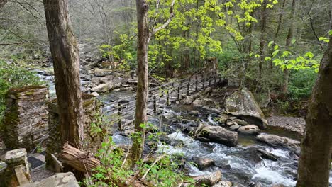 View-of-wooden-suspension-bridge-crossing-over-creek,-West-Virginia