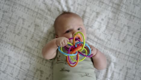 Baby-Caucasian-boy-playing-with-a-colorful-toy-on-a-white-play-mat