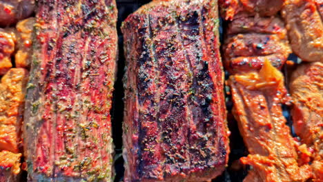 Close-up-of-delicious,-seasoned-meats-grilling-to-perfection-on-a-BBQ,-ideal-for-culinary-enthusiasts-and-summer-gatherings,-pull-back-reveal-from-charred-meat-with-grill-marks