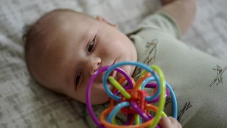 Baby-Caucasian-boy-playing-with-a-colorful-toy-on-a-white-play-mat