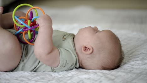 Baby-Caucasian-boy-playing-with-a-colorful-toy-on-a-white-play-mat