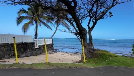 POV-From-of-sea,-car-driving-along-the-picturesque-coastal-road-above-dramatic-rocky-shore-towards-beautiful-volcanic-mountains