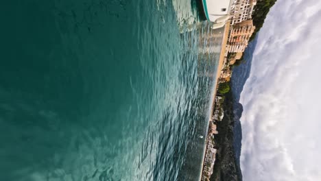 Crystal-clear-waters-with-mountains-and-buildings-in-the-background,-Soller,-Mallorca