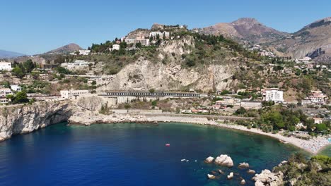 Scenic-coastal-town-with-rocky-hills-and-clear-blue-waters,-shot-from-above