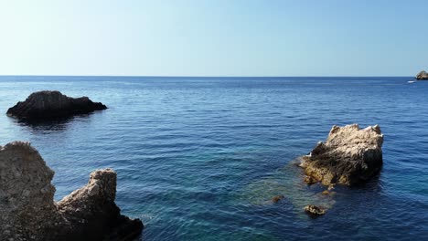 Crystal-clear-blue-sea-with-rocky-outcrops-under-a-clear-sky