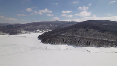 Drone-footage-of-Macedonia's-winter-scenery,-featuring-snowy-mountains-and-a-frozen-lake