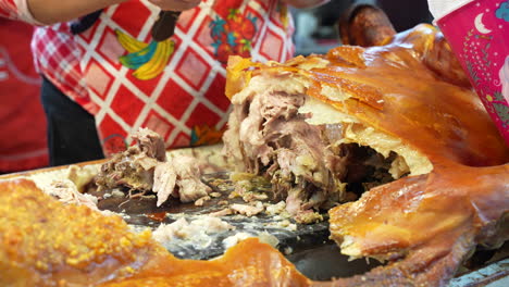 Manos-De-Una-Señora-Cortando-La-Piel-Cocida-De-Toda-La-Pieza-De-Cerdo,-Comida-En-Ecuador