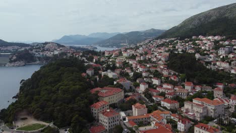 Große-Häuser-Mit-Orangefarbenen-Dächern-In-Hügeliger-Landschaft-In-Dubrovnik,-Kroatien,-Luftaufnahme