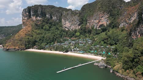 High-angle-aerial-shot-capturing-small-town-situated-at-shore-of-Pai-Plong-Beach-in-Krabi,-Thailand