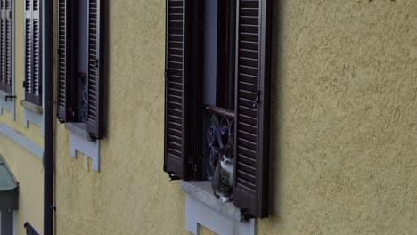 Gato-Sentado-En-El-Alféizar-De-Una-Ventana-Con-Contraventanas-En-Un-Antiguo-Edificio-Italiano-En-Una-Pequeña-Ciudad