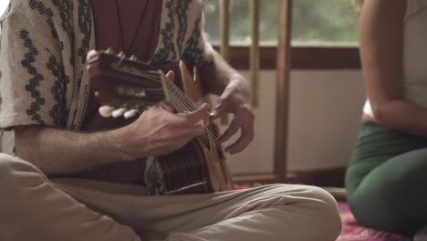 Primer-Plano-De-Un-Hombre-Tocando-La-Guitarra-En-El-Interior,-Ritual-Relajante-De-Sanación-Con-Sonido