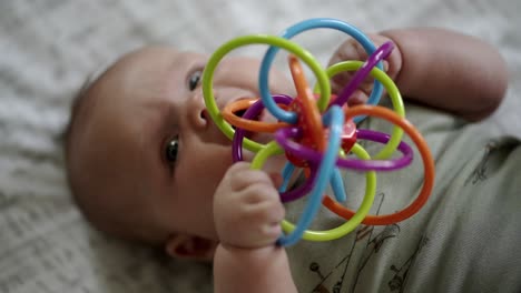 Baby-Caucasian-boy-playing-with-a-colorful-toy-on-a-white-play-mat