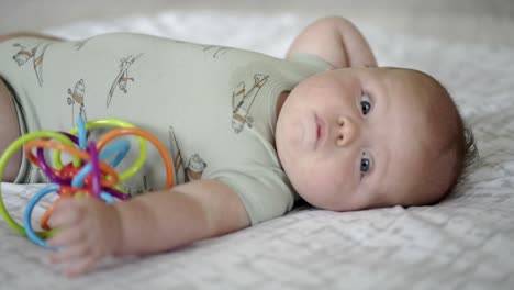 Baby-Caucasian-boy-playing-with-a-colorful-toy-on-a-white-play-mat