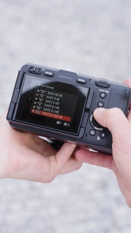 Vertical-shot-of-person-hold-camera-and-change-recording-settings,-Czechia