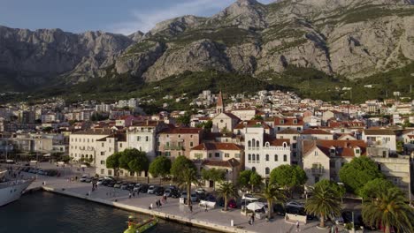 Makarska,-Croatia-waterfront-with-boats-docked-and-scenic-mountain-backdrop,-aerial-view