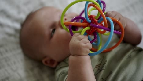 Baby-Caucasian-boy-playing-with-a-colorful-toy-on-a-white-play-mat