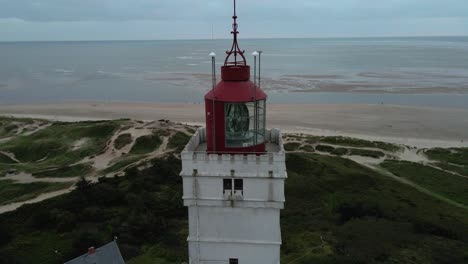 Primer-Plano-De-Una-Toma-Aérea-Con-Dron-Que-Gira-En-Sentido-Antihorario-Alrededor-De-La-Parte-Superior-Del-Faro-De-Blåvand,-Con-La-Baliza-Apagada