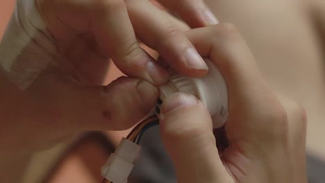 Close-up-to-bandaged-hand-checking-the-electrical-cables-and-wiring-of-a-motion-sensor-bulb