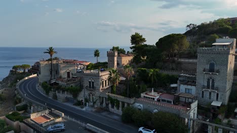 Coastal-castle-with-scenic-ocean-backdrop-and-clear-blue-sky,-aerial-view