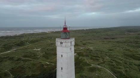 Weite-Drohnenaufnahme,-Die-Gegen-Den-Uhrzeigersinn-Um-Die-Spitze-Des-Leuchtturms-Von-Blåvand-Kreist,-Leuchtfeuer-Ausgeschaltet