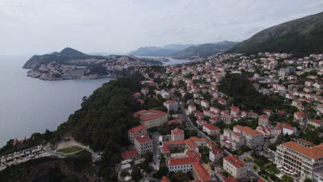 Drone-rising-over-cityscape-and-island-panorama,-Dubrovnik,-Croatia,-cloudy-day