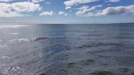 Das-Video-Zeigt-Eine-Weitwinkelaufnahme-Des-Ozeans-Mit-Blauem-Himmel-Und-Weißen-Wolken,-Tiefblauem-Wasser-Und-Sanft-Rollenden-Wellen