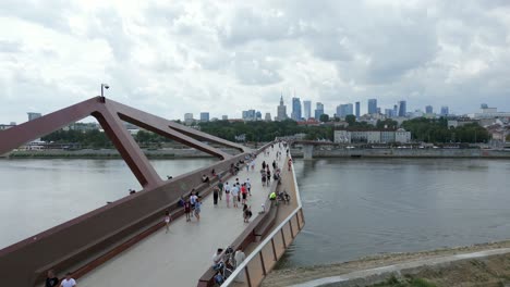 People-lost-in-thoughts-and-conversation-crossing-bridge-structure,-aerial