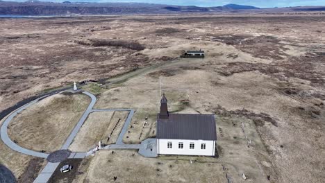 Imágenes-Aéreas-De-La-Iglesia-De-Strandarkirkja-Con-Impresionantes-Vistas-De-La-Costa-Y-Un-Camino-Pavimentado-Que-Conduce-A-Un-Cementerio-Tranquilo-Y-Al-Océano.