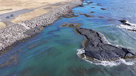 Las-Imágenes-Aéreas-Muestran-La-Costa-Cerca-De-La-Iglesia-De-Strandarkirkja-Con-Agua-Azul-Clara-Y-Acantilados-Rocosos.