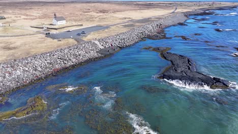 Das-Video-Zeigt-Die-Küste-In-Der-Nähe-Der-Strandarkirkja-Kirche-Mit-Ihrer-Rauen-Schönheit-Und-Dem-Klaren-Blauen-Wasser