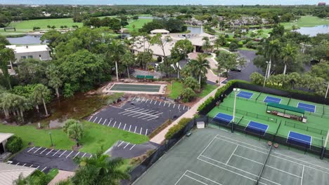 Vuelo-Aéreo-Sobre-El-Campo-De-Tenis,-Zona-Deportiva-Con-Río-Y-Campo-De-Golf