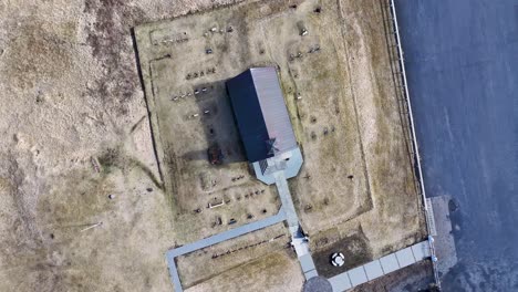 Pequeña-Iglesia-En-Una-Colina-Con-Vista-Al-Océano,-La-Costa-De-Islandia,-Un-Cementerio-Tranquilo-Y-Un-Camino-Pavimentado-Que-Conduce-A