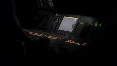 Sound-engineer-working-on-mixing-desk-at-a-live-concert-at-night