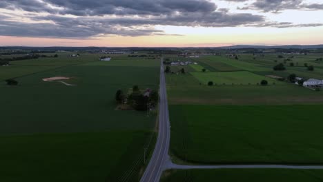 High-angle-flight-over-rural-road-in-american-countryside-at-dusk