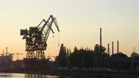 Gdansk-shipyard-with-cranes-and-industrial-buildings-with-chimneys,-in-sunset-light