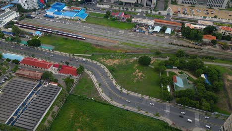 Phnom-penh-with-roads,-greenery,-and-rail-tracks-in-an-urban-area,-aerial-view