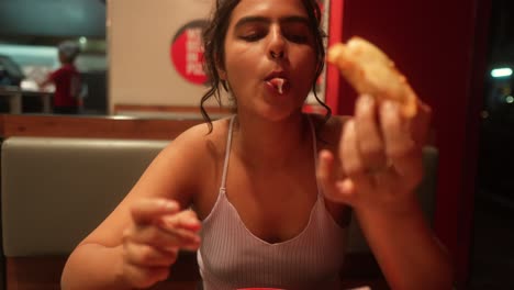 Woman-enjoys-eating-a-meal-in-a-cozy-restaurant-booth-at-night