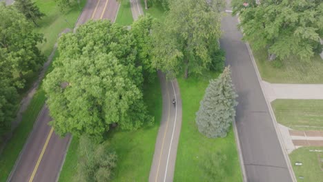 Aerial-follow-up-shot-of-a-cyclist-cycling-through-pathways-in-Minnesota,-USA