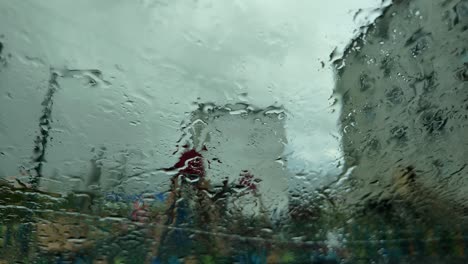 Rain-pours-gently,-blurring-the-vibrant-colors-of-the-streets-while-city-dwellers-move-about-under-the-grey-clouds